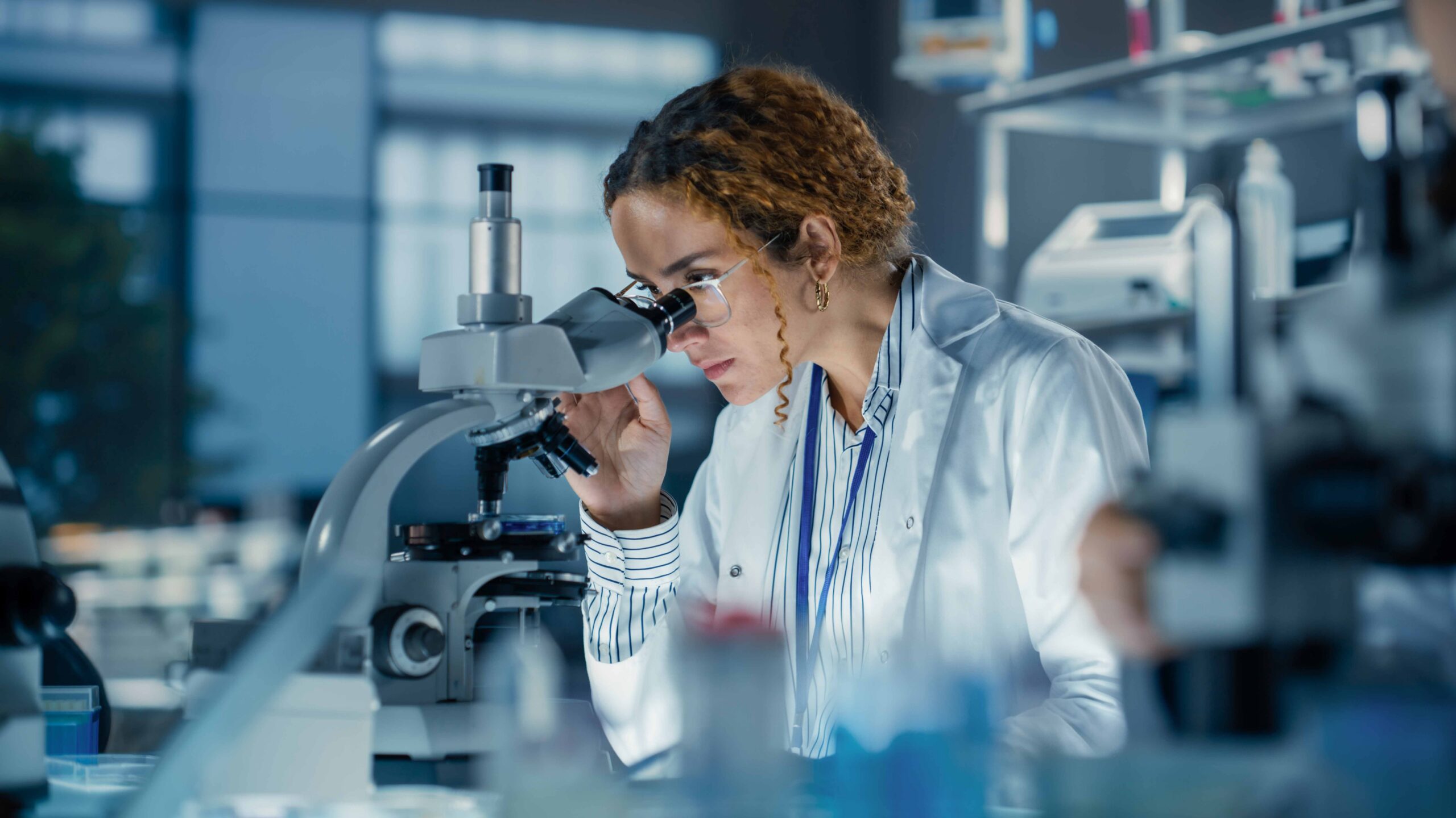 Scientist Conducting Laboratory Research Scientist Examining A Sample Through A Microscope In A Laboratory