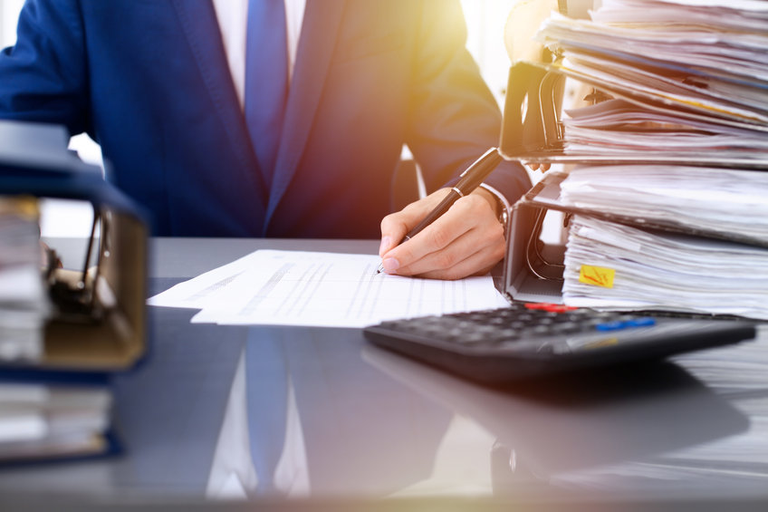 Bookkeeper or financial inspector and secretary making report, calculating or checking balance. Internal Revenue Service inspector checking financial document. Business, tax and audit concepts First Solo Image